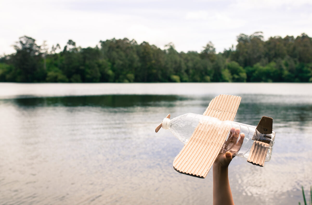 Child holding plane made of recycled materials